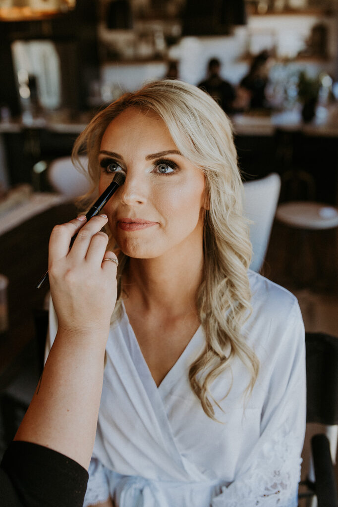 bride getting her makeup done before her ceremony 
