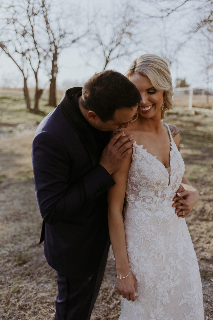 groom kissing the bride on the shoulder | Kelli and Adam's Wedding Day At Bethel Rock, Texas