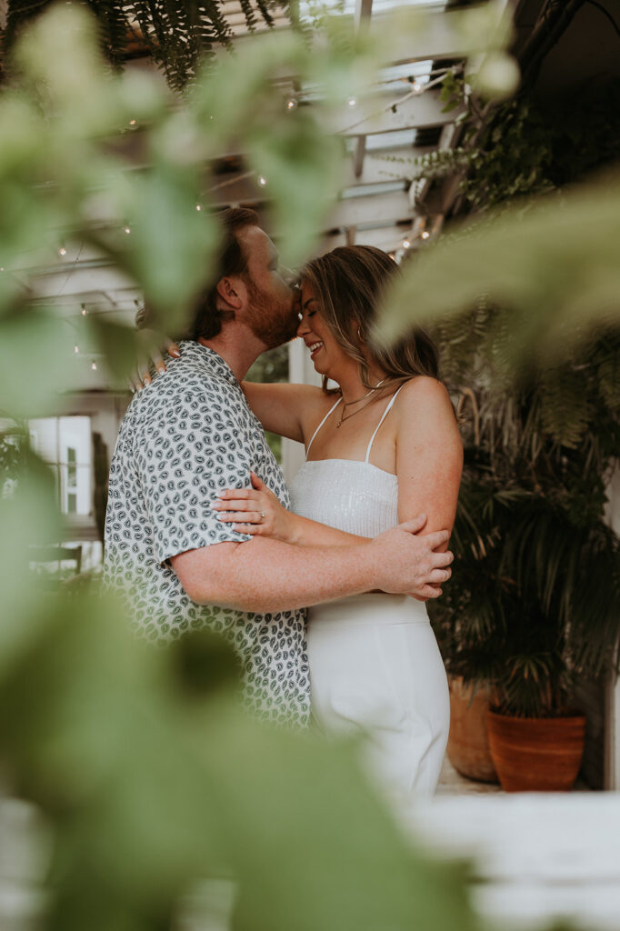 Couple kissing in the forehead during their unique engagement photoshoot