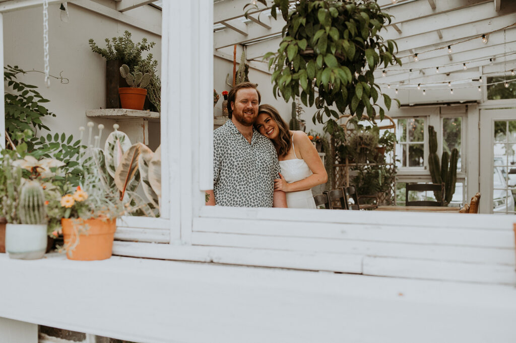 beautiful couple at house of dirt with plants in the background during their unique engagement photoshoot