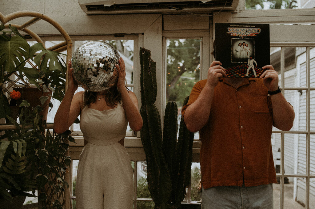 couple holding a cd record and a disco ball in front of their face at House of Dirt