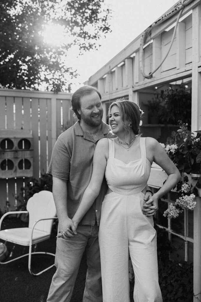 Black and white photo of a couple smiling at each other at House of dirt during their engagement photos