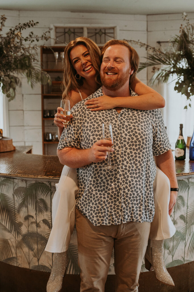 Couple hugging each and sharing champagne at their unique engagement photos