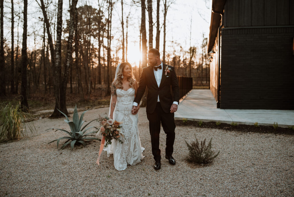 beautiful bride and groom walking and holding hands with the sunset in the background 