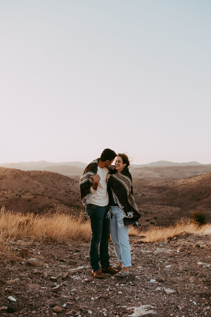 couple hugging wearing a blanket during their adventurous engagement photoshoot 