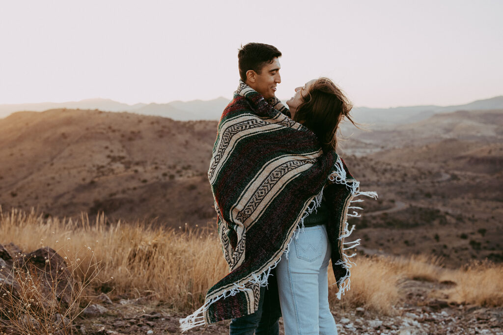 couple using a blanket during their adventurous engagement photoshoot