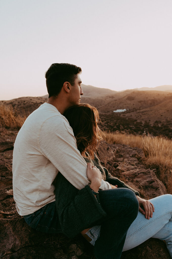 couple looking at the sunset during their adventurous engagement photoshoot 