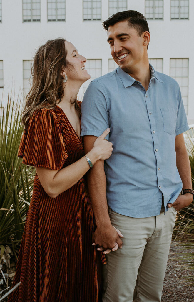 couple smiling and looking at each other in Marfa, Texas during their adventurous engagement photoshoot 