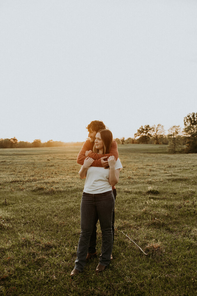 engaged couple hugging with the sun in the background