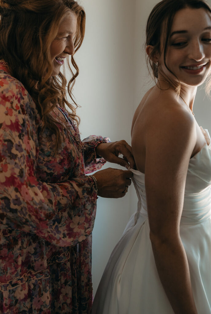 mother of the bride helping her with the wedding dress 