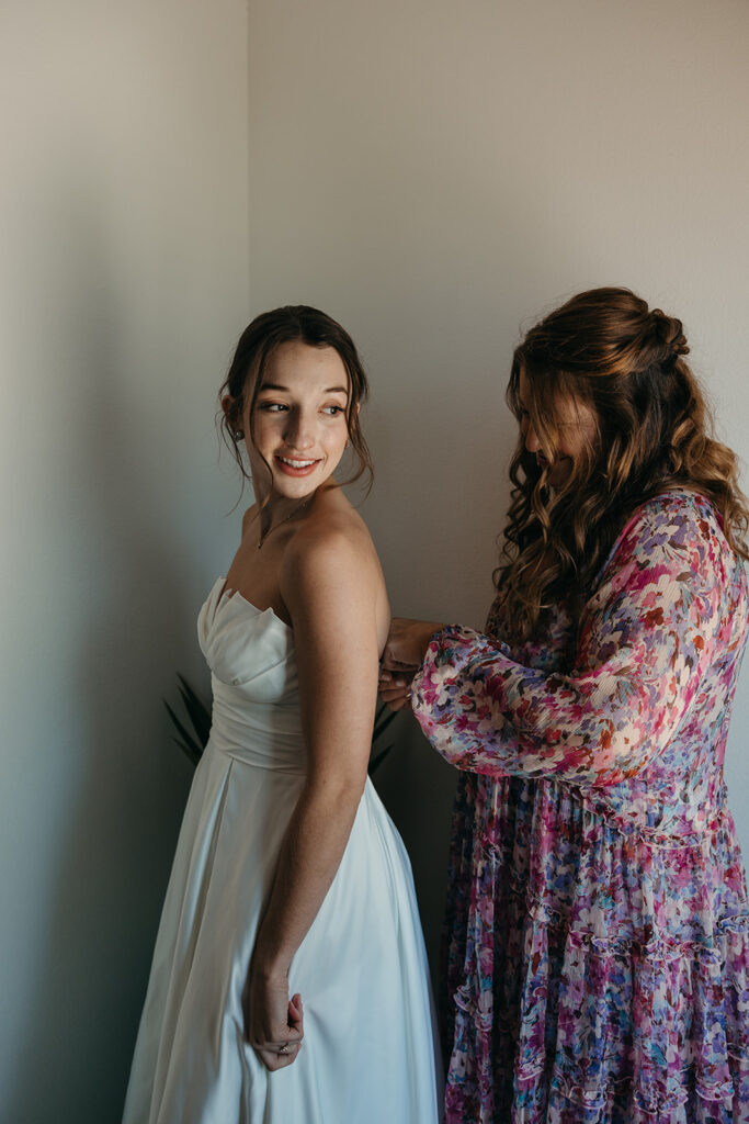 mother of the bride helping her with her wedding dress for her Luxurious Wedding Day 