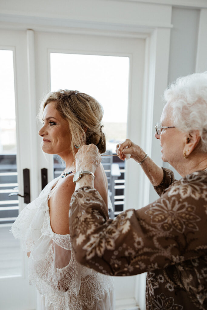 grandma helping the bride with her wedding necklace 