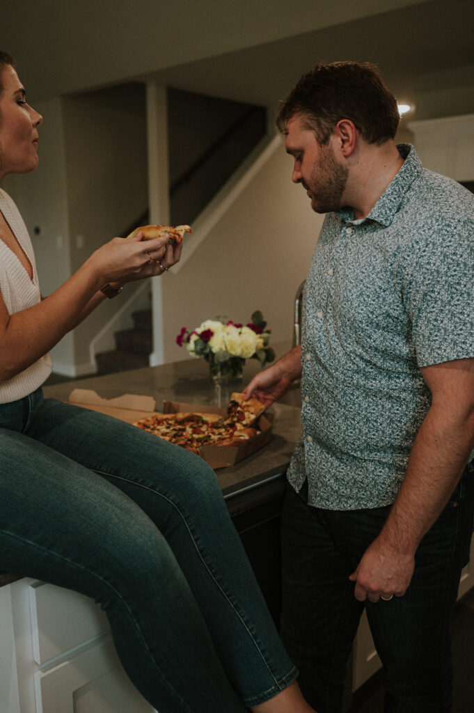cute couple eating pizza at their first home session 